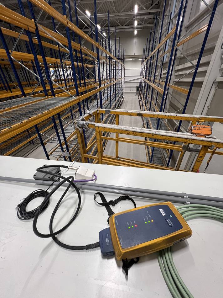 Cablecertificatie met een Fluke-tester in een magazijn met stellingen