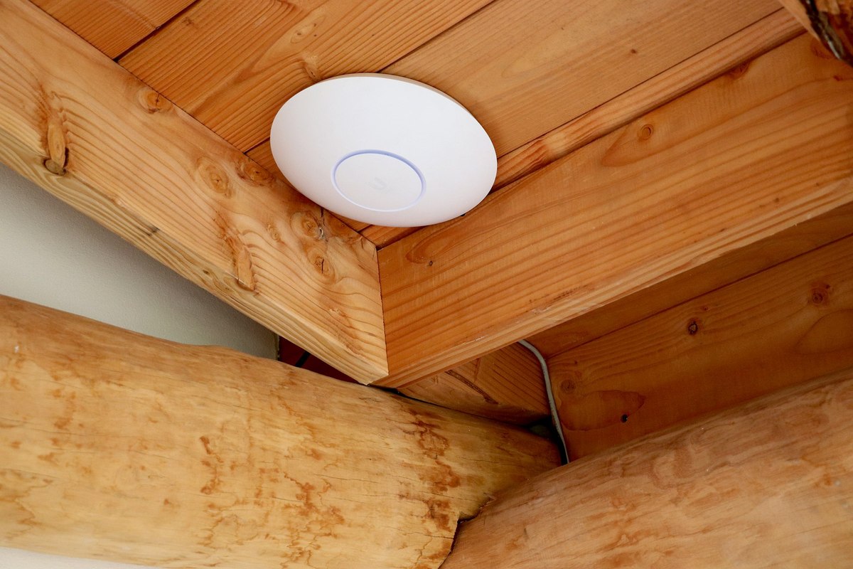 UniFi accesspoint gemonteerd onder een houten overkapping in de tuin
